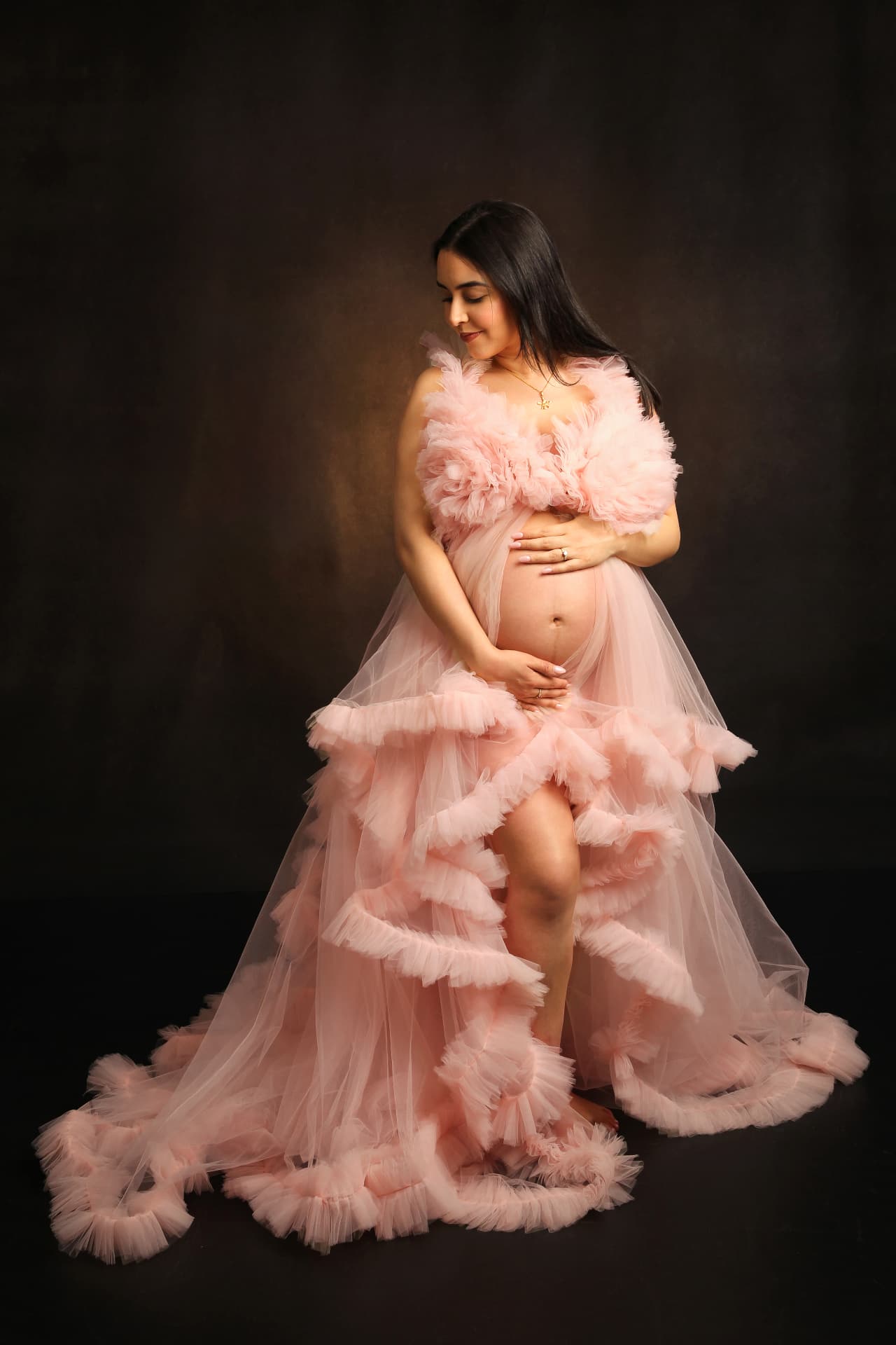 Dramatic studio maternity portrait in a flowing blush tulle gown